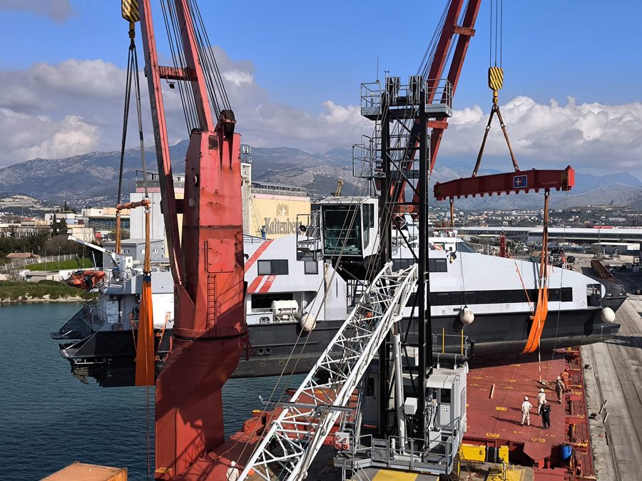 Ferry rapide hissé par les grues d'un cargo à quai