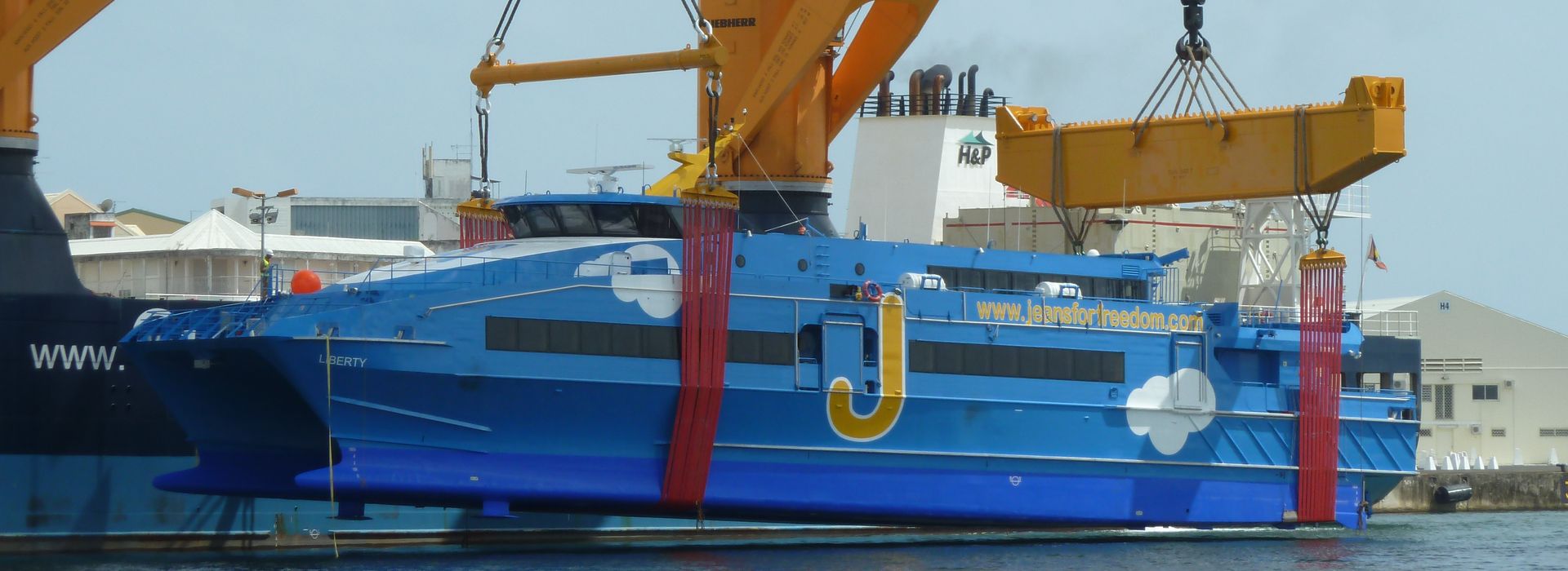 Ferry rapide bleu « Liberty » levé par la grue d'un cargo