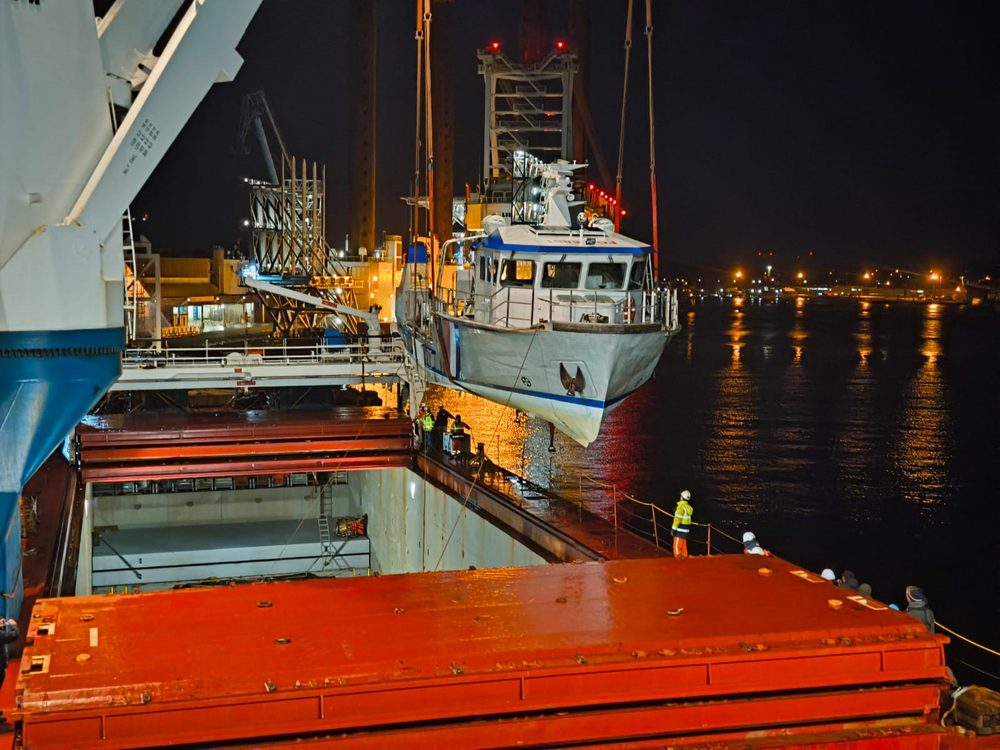 Vedette hissée de nuit au-dessus du pont d'un cargo, à l'aplomb de la cale