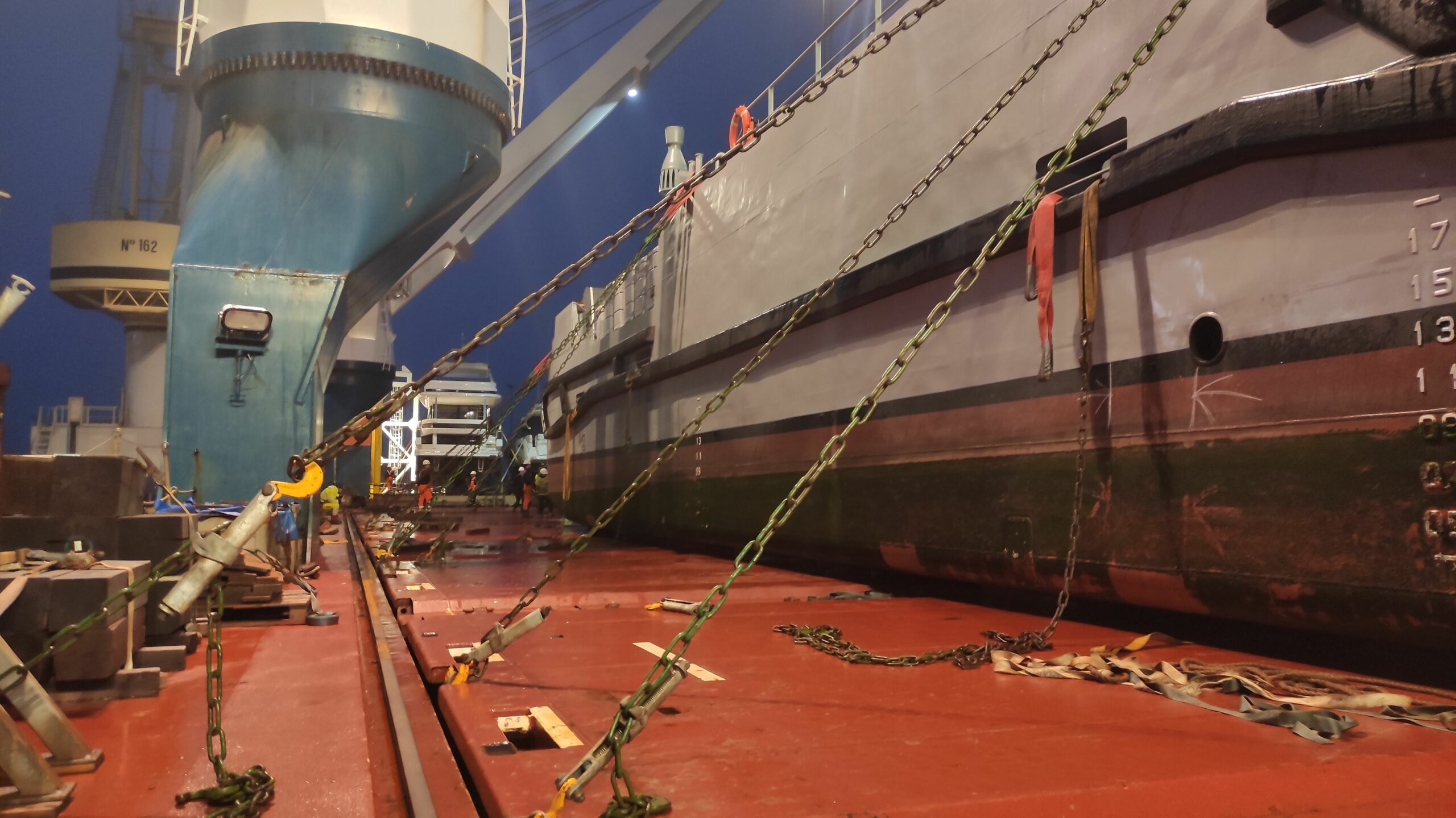 Chaînes de saisissage tendues de nuit sur le pont d'un cargo, le long de la coque